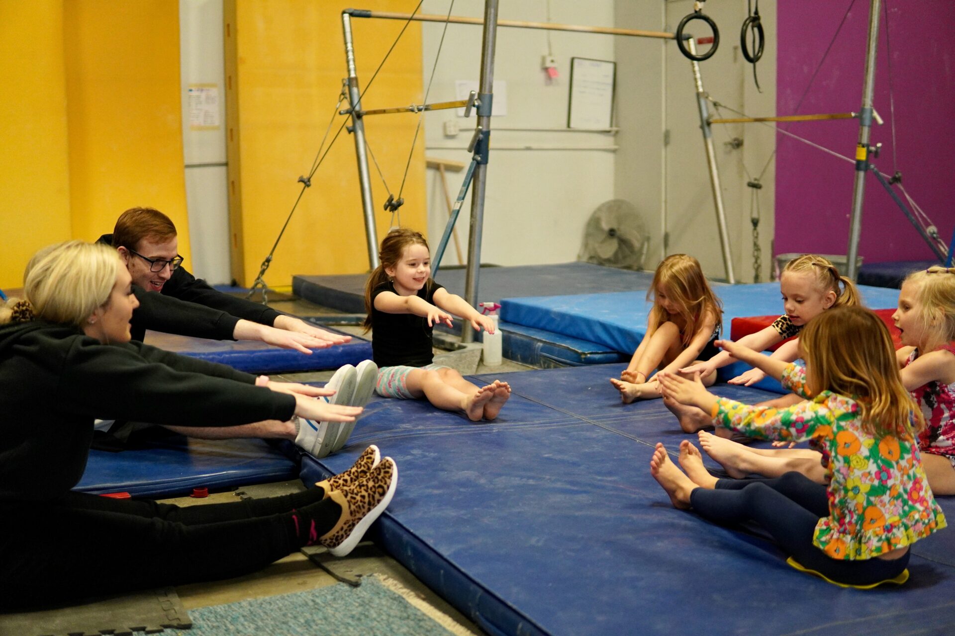 A group of people sitting on the floor in a gym.